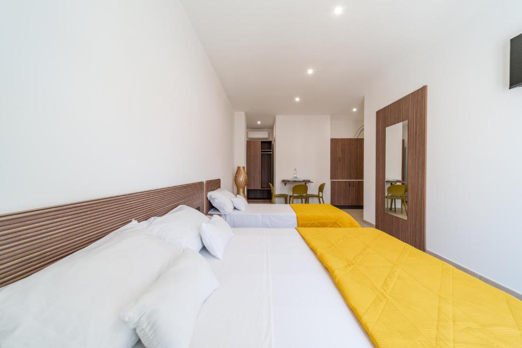 a bedroom with two beds with white and yellow sheets at Costamar Vacanze in Lido Marini