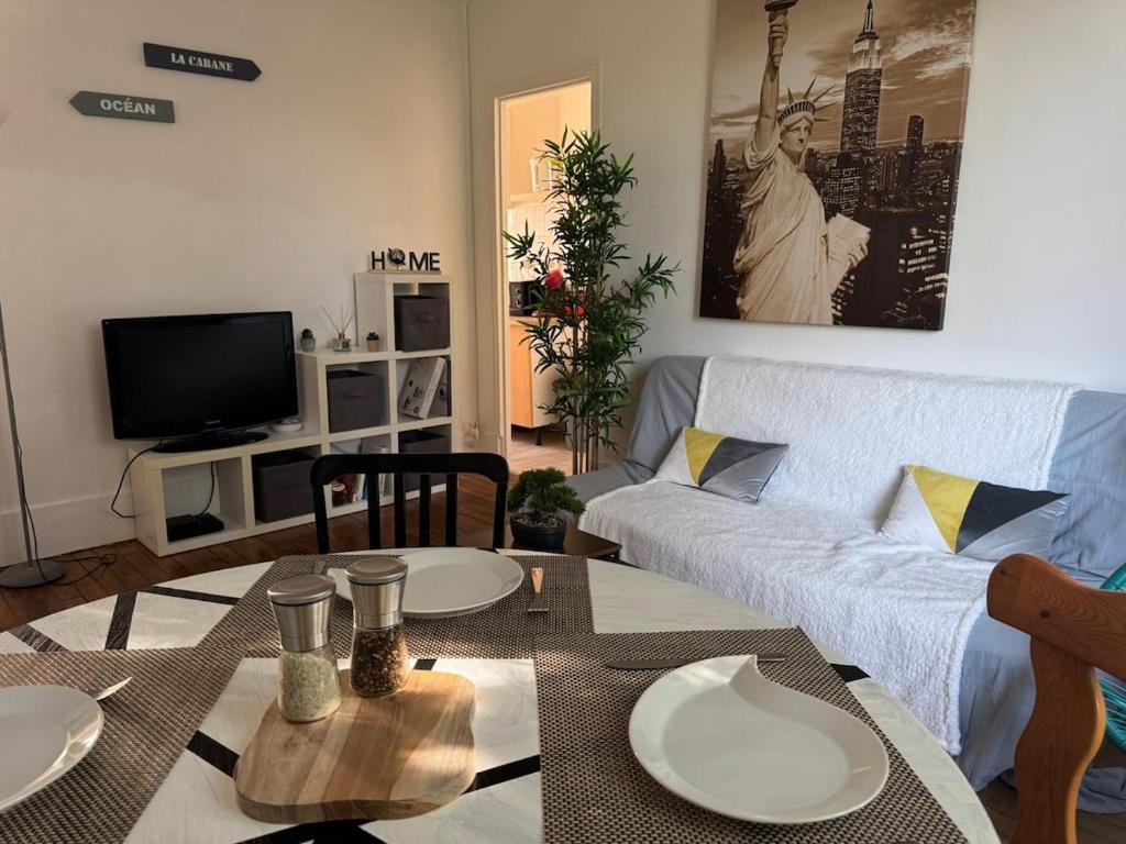 una sala de estar con un sofá y una mesa en Cozy appartement 2 chambres au coeur de Palaiseau 8min RER B à pieds, en Palaiseau