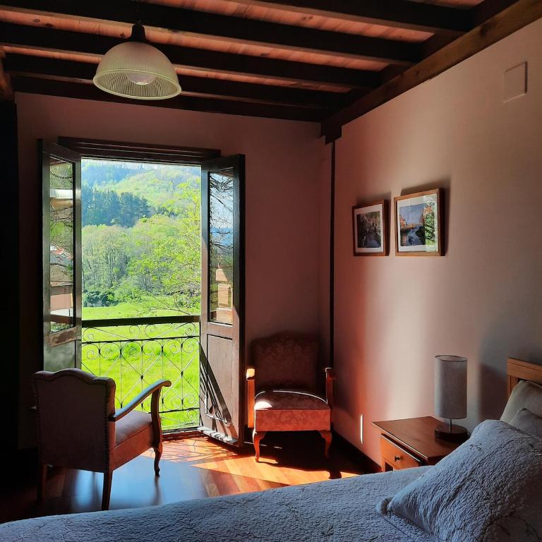 a bedroom with a bed and a large window at La Casina del Pintor in Robledo