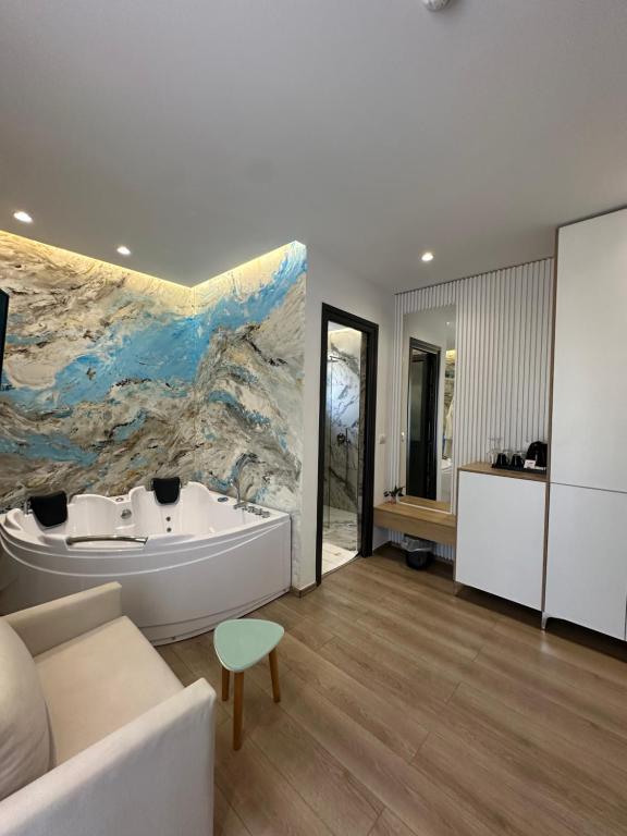 a bathroom with a white tub and a large painting on the wall at Ilio Boutique Hotel in Ksamil