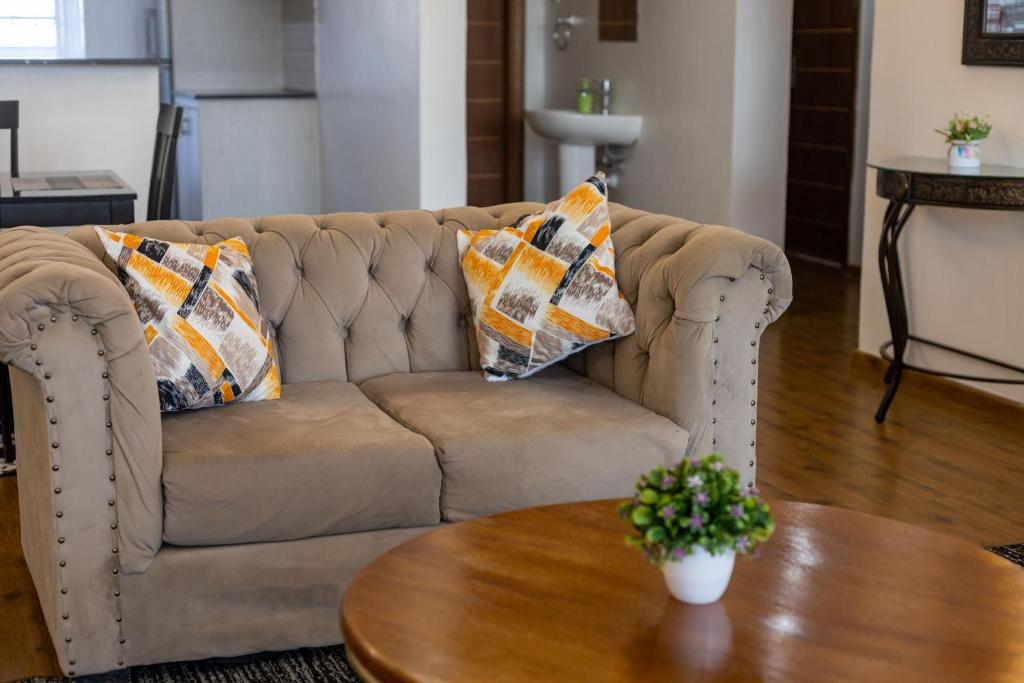 a couch with pillows and a table in a living room at Erica Residences - Riverside in Nairobi