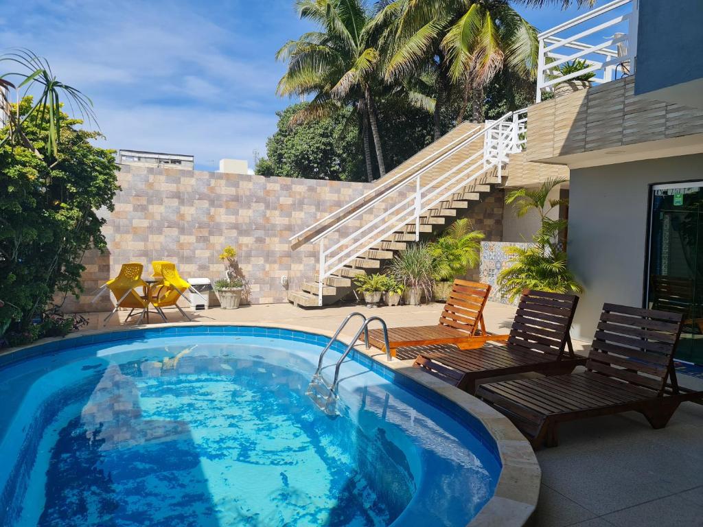 una piscina con dos sillas y una casa en Pousada Raízes Do Porto, en Porto de Galinhas