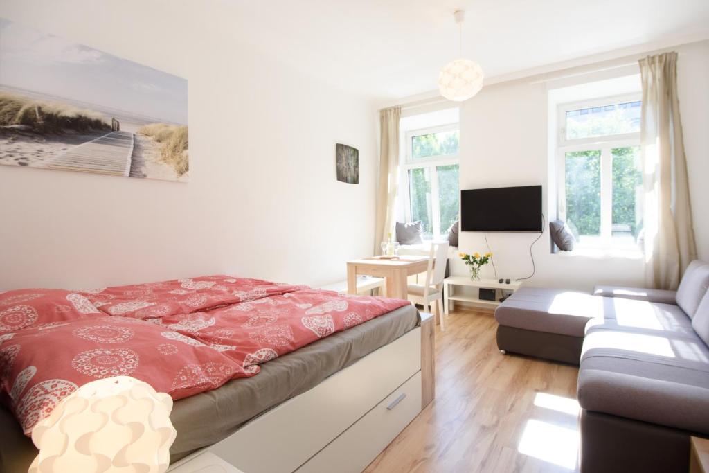 ein Schlafzimmer mit einem roten Bett und einem Sofa in der Unterkunft Vienna Living Apartments - Kempelengasse in Wien