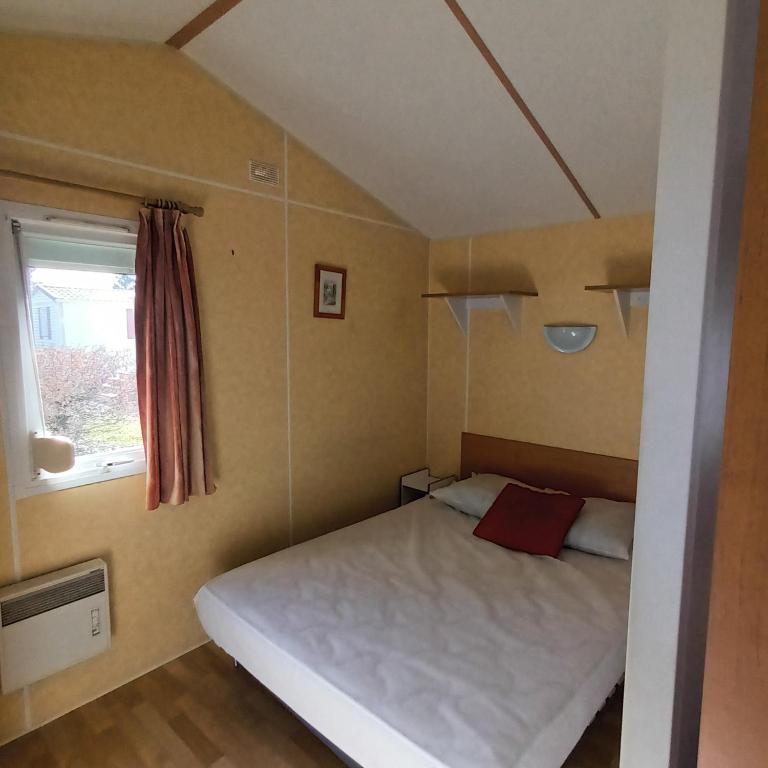 een kleine slaapkamer met een wit bed en een raam bij Camping Baroudeurs in Lagraulière