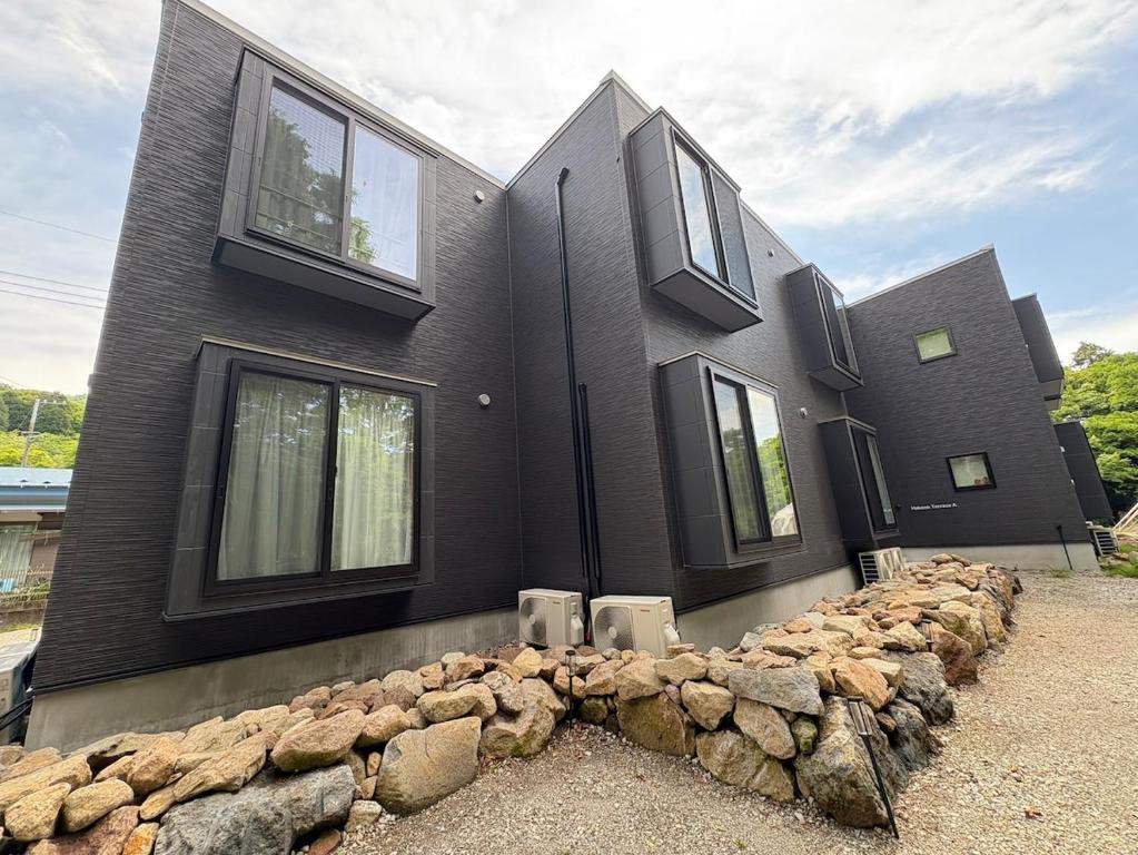 a black house with a bunch of rocks in front of it at ハーモニーヒルズVilla箱根強羅 in Hakone