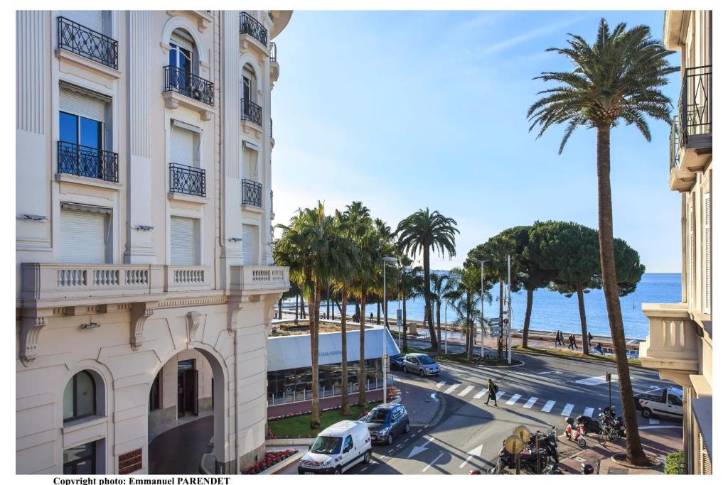 un bâtiment et une rue avec des palmiers et l'océan dans l'établissement REF 961 - Cannes Croisette - Sea view apartment for rent, à Cannes