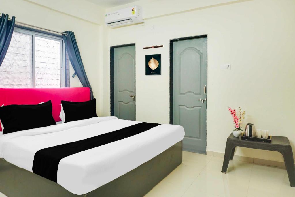 a bedroom with a large bed with a pink headboard at Hotel O Laxmi Chowk Hinjewadi in Pune