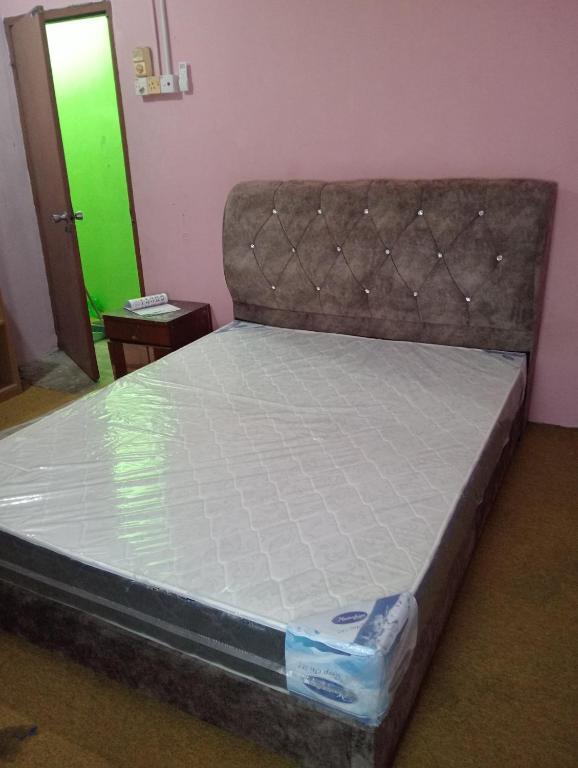 an empty bed in a room with a green door at Nazd guest house in Kijal