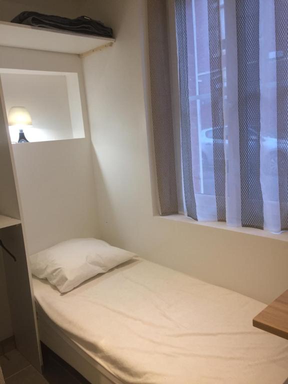 un petit lit dans une chambre avec une fenêtre dans l'établissement Studette refaite à neuf, à Amiens