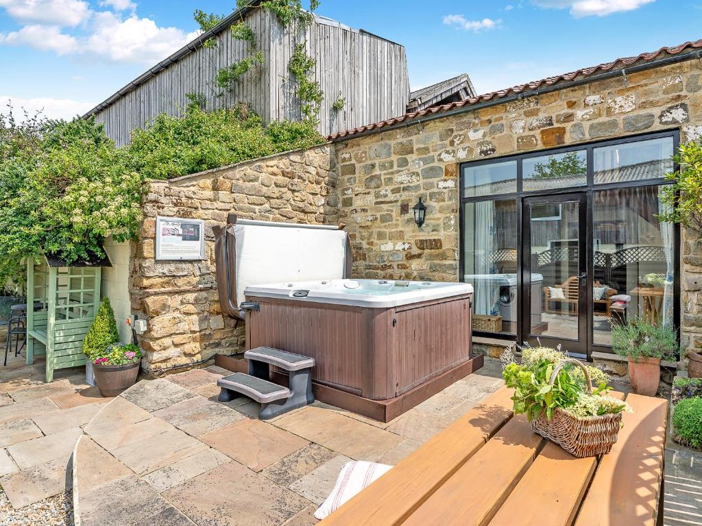 a hot tub in the backyard of a stone house at The Dairy in Beck Hole
