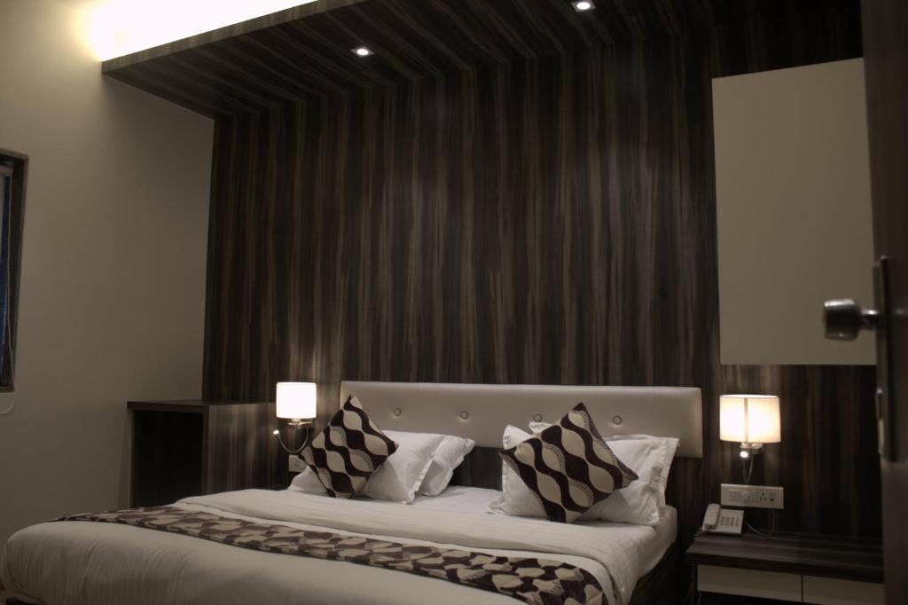 a bedroom with a large bed with black and white pillows at Hotel Sai Sanidhya in Thane