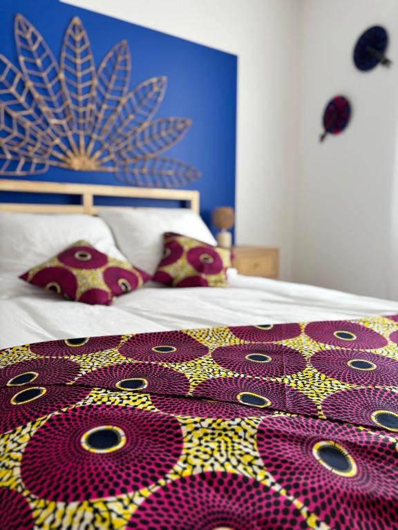 - un lit avec une couette et des oreillers colorés dans l'établissement La case sénégalaise, à Cholet