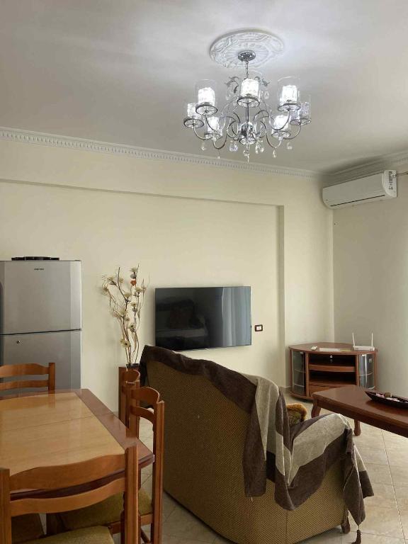a living room with a couch and a table and a chandelier at Klara's Apartment in Fier