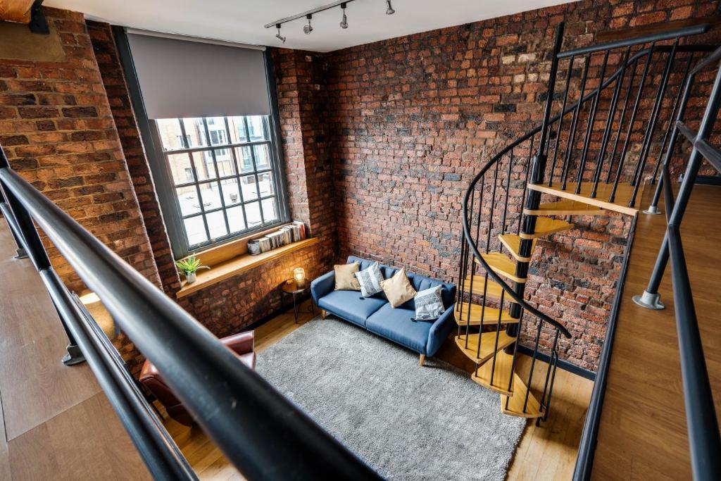 a brick room with a staircase and a blue couch at Liverpool Warehouse Flat - Sleeps 5, WiFi, Free On-Site Parking in Liverpool