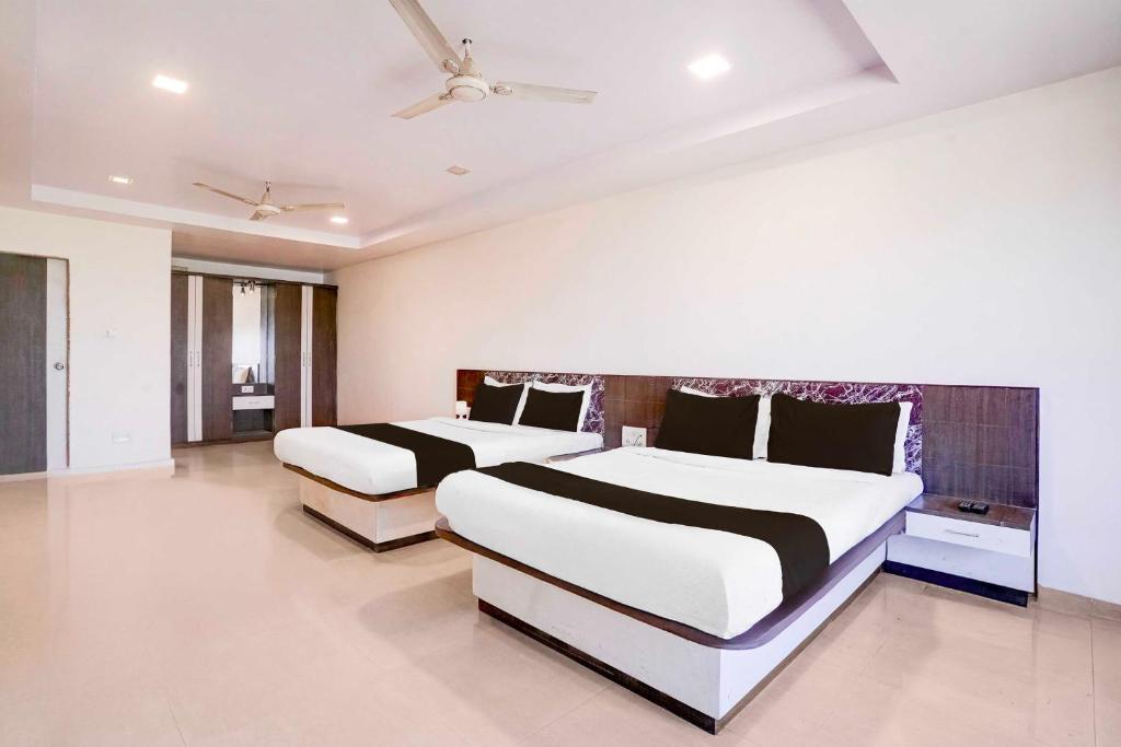 a bedroom with two beds and a ceiling fan at Hotel O Mahableshwar Uptown in Mahabaleshwar