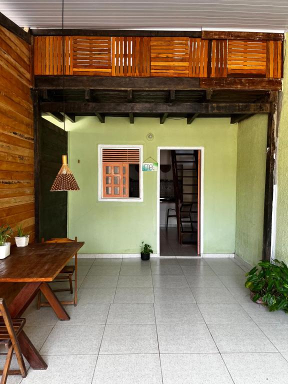 an open patio with a wooden table and a house at MeldoMar chalé aconchegante na Pipa in Pipa