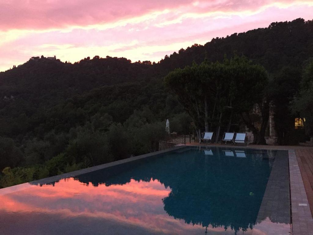 une piscine avec un coucher de soleil en arrière-plan dans l'établissement Splendide authentique Mas, à Cabris