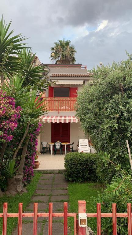 a house with a balcony and a table and chairs at Stone beach holiday home in Mascali
