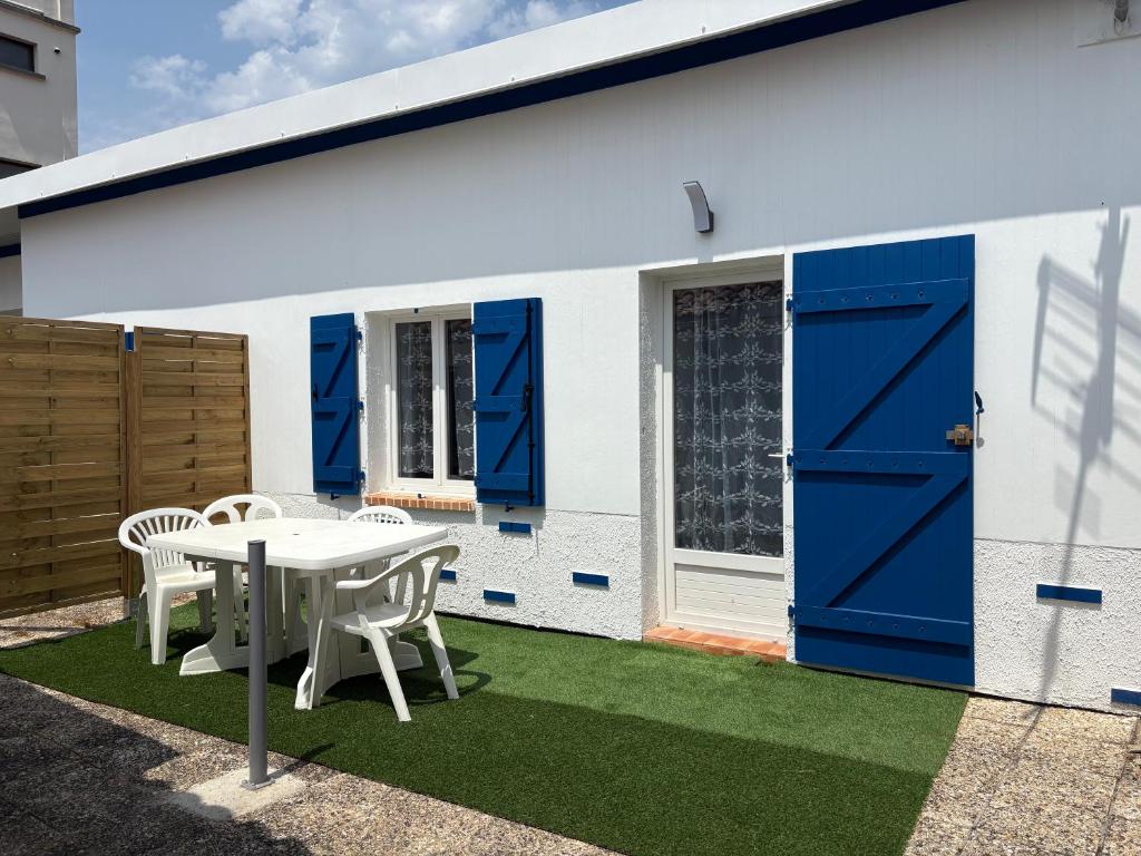 une maison avec des portes bleues, une table et des chaises dans l'établissement Ombre et Vague, à Mimizan-Plage