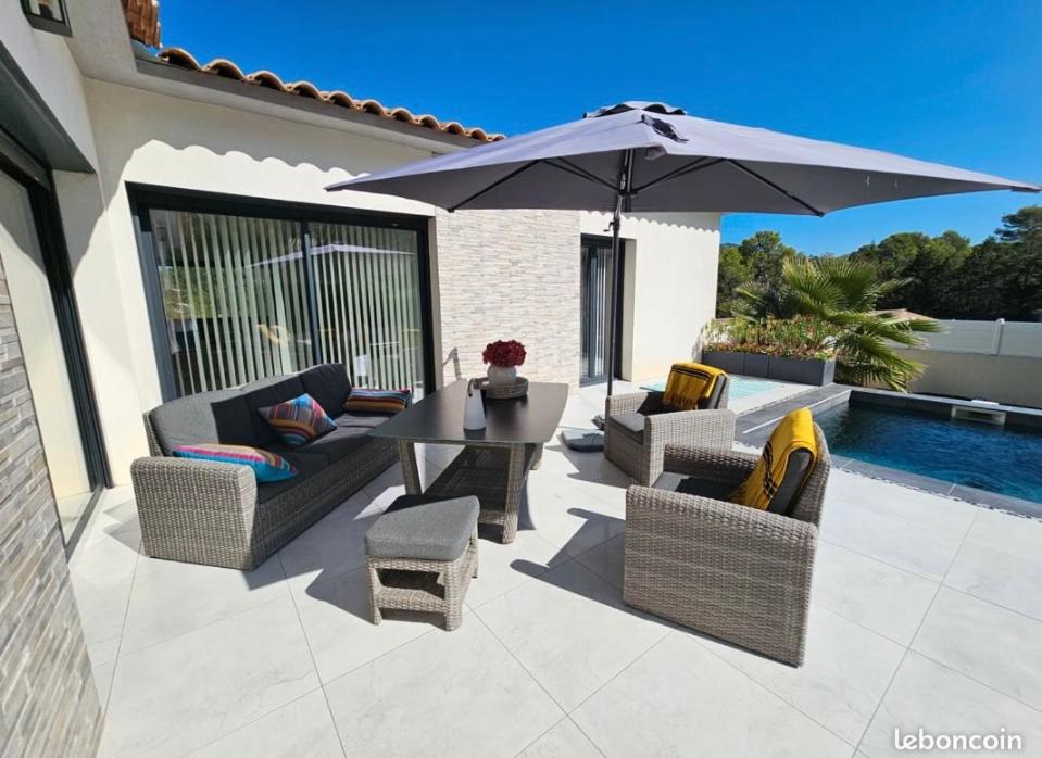 un patio avec une table, des chaises et un parasol dans l'établissement Magnifique, villa, spacieuse et lumineuse, à Rocbaron