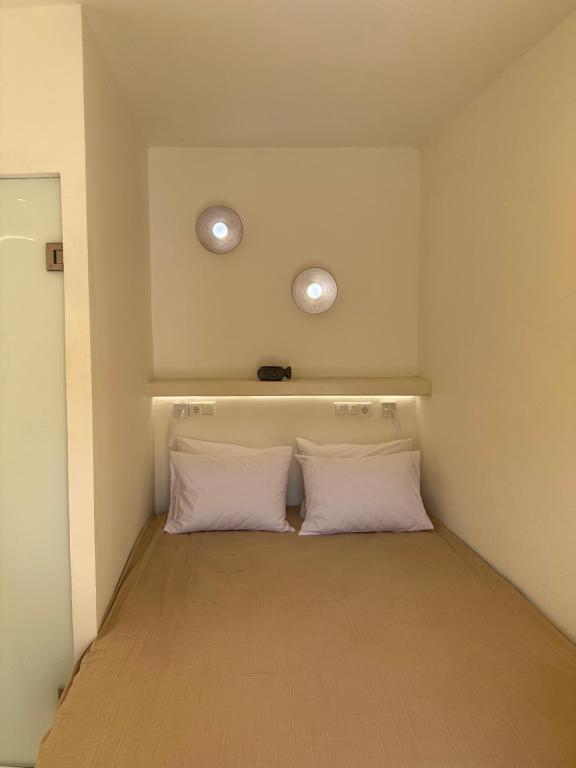 een slaapkamer met twee witte kussens en twee lampen bij Marias Home in Kithnos