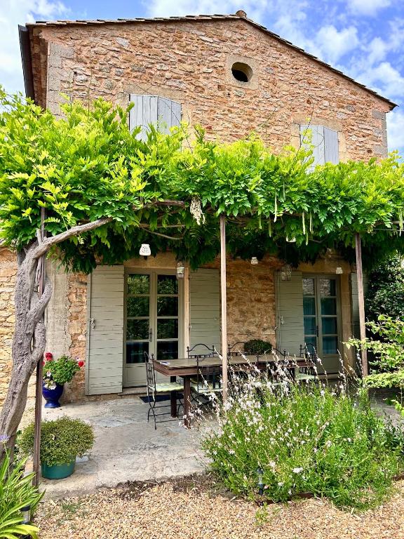 une maison en briques avec une table et un banc devant elle dans l'établissement La maison de Nôtre Dame 6, à Aigaliers