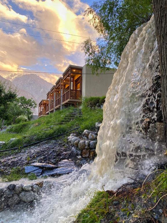 a house on a hill next to a waterfall at Diwan-e-Hunza Resort in Gulmit