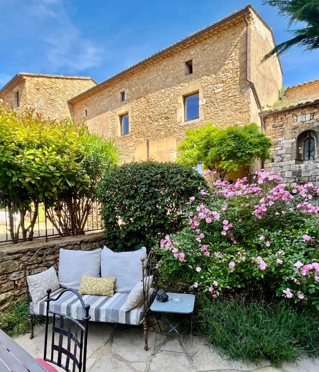 un canapé assis devant un bâtiment avec des fleurs dans l'établissement Gîte les hirondelles, à Aigaliers