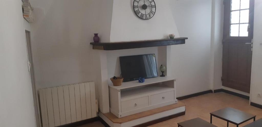 - un salon avec une télévision et une horloge murale dans l'établissement La jovine, à Oupia