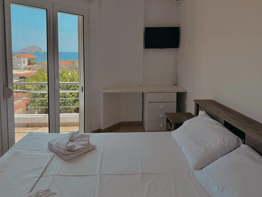 a bedroom with a large white bed and a balcony at Seaview Complex with Pool in Porto Rafti