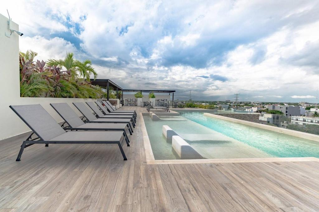 a row of lounge chairs sitting on the roof of a building at Condo Verde Oasis - Central 2 bedroom with pool, gym, private terrace - At Veranto Condos in Playa del Carmen