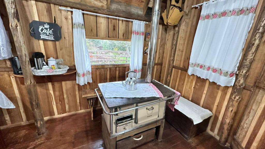 a kitchen with a stove and a sink in a cabin at Chalé Xodó da Serra Urubici in Urubici