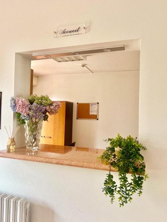 un miroir avec un vase de fleurs sur un comptoir dans l'établissement Résidence Hôtelière du Magnoac, à Castelnau-Magnoac