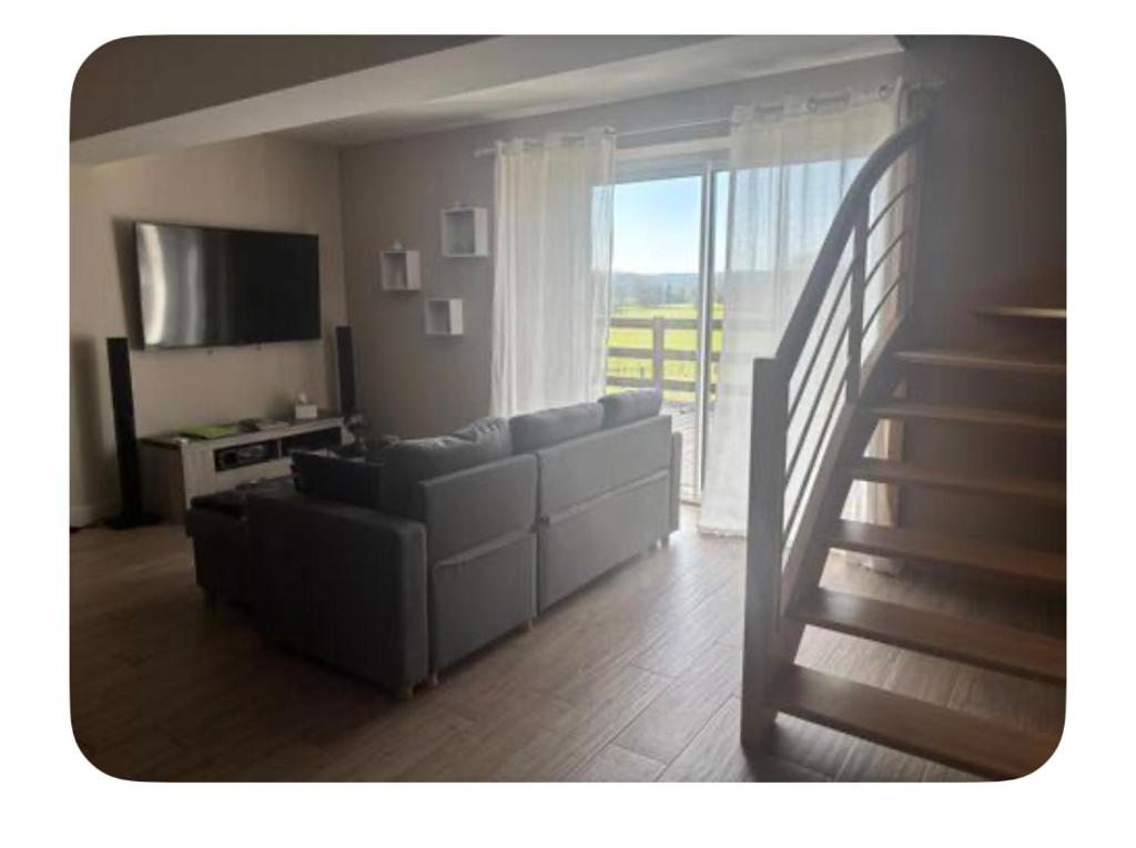 sala de estar con sofá, TV y escalera en La maison du bonheur au cœur du Morvan, en Moux-en-Morvan