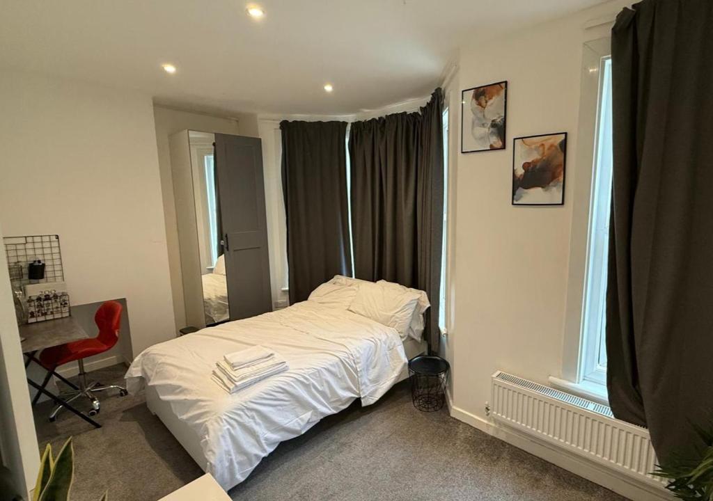 una camera da letto con un letto bianco e una finestra di Peeams Abode Erith a Erith