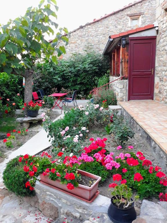 un jardin avec des fleurs roses et une porte rouge dans l'établissement Gîte Au Bonheur des Hôtes en Auvergne, à Égliseneuve-près-Billom