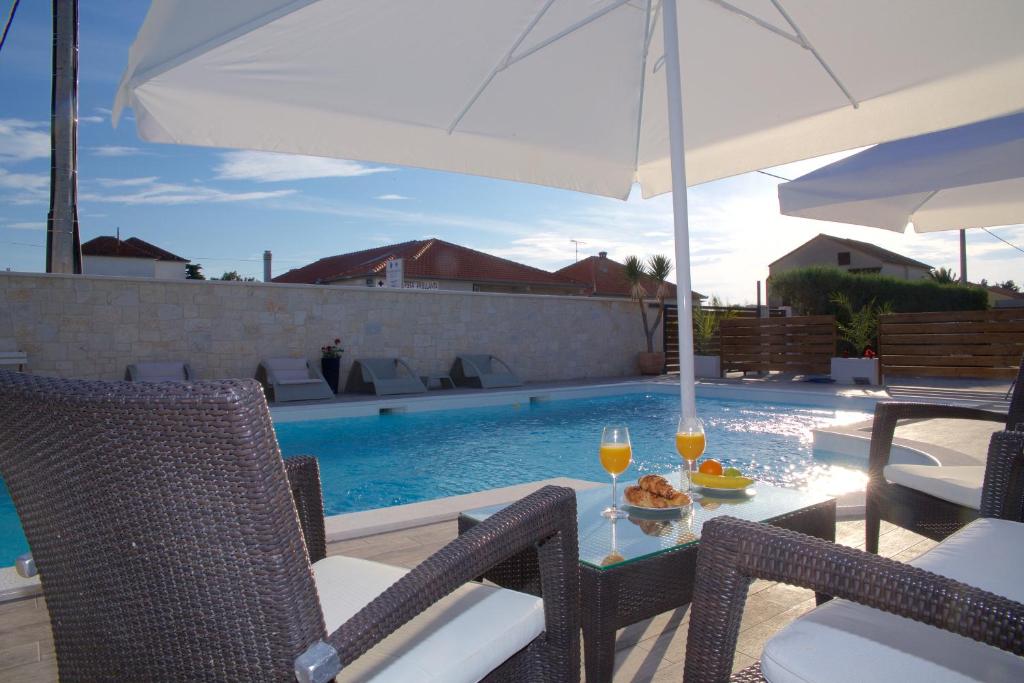 a patio with a table with two glasses of wine at Banić Apartments with pool in Biograd na Moru