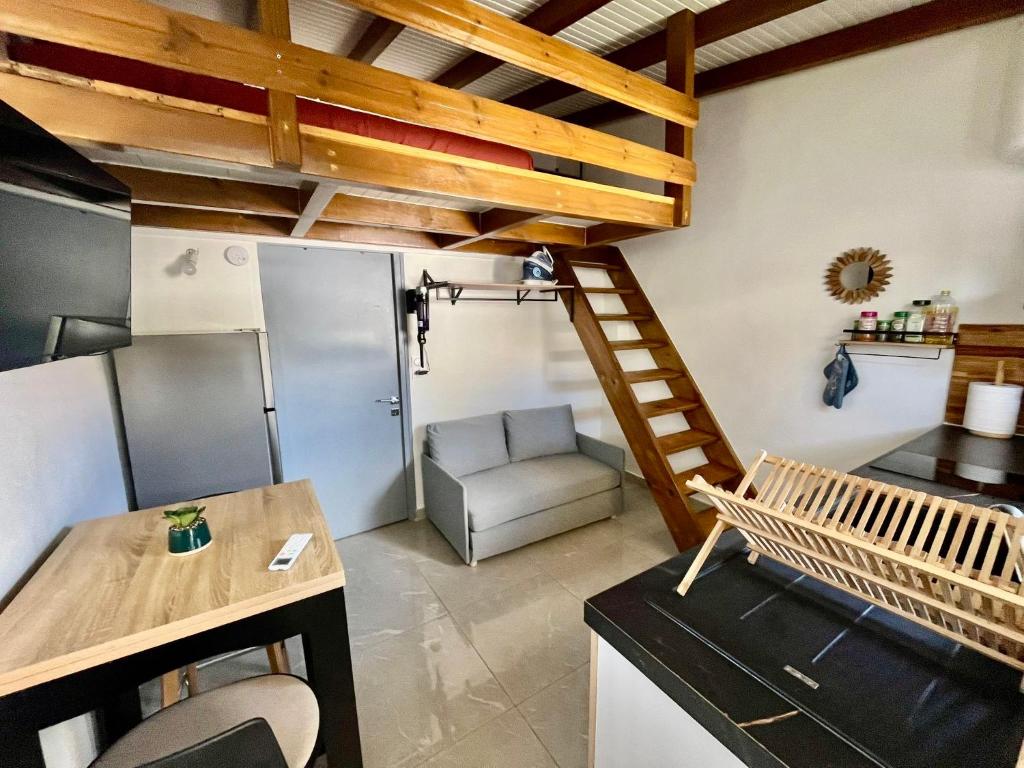 a living room with a staircase and a chair at Studio cosy équipé à 5min de la plage in Vieux-Habitants