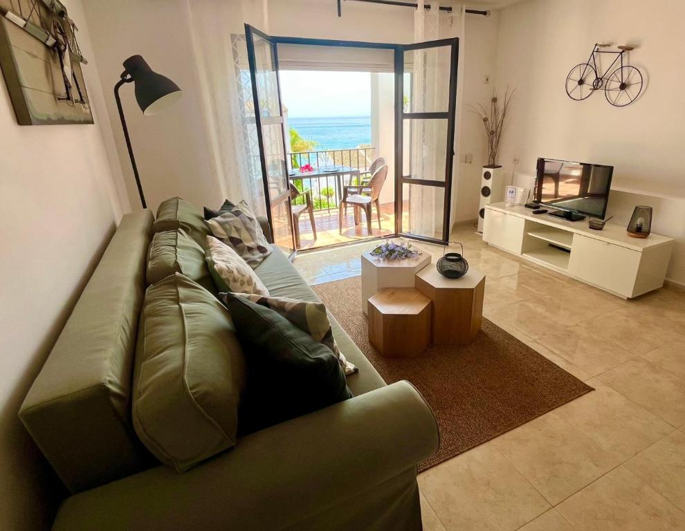 a living room with a green couch and a view of the ocean at Donalolaplaya in Mijas Costa