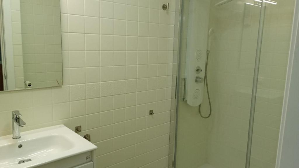 a white bathroom with a shower and a sink at Dúplex Casa Ana Apartaclub La Barrosa in Chiclana de la Frontera