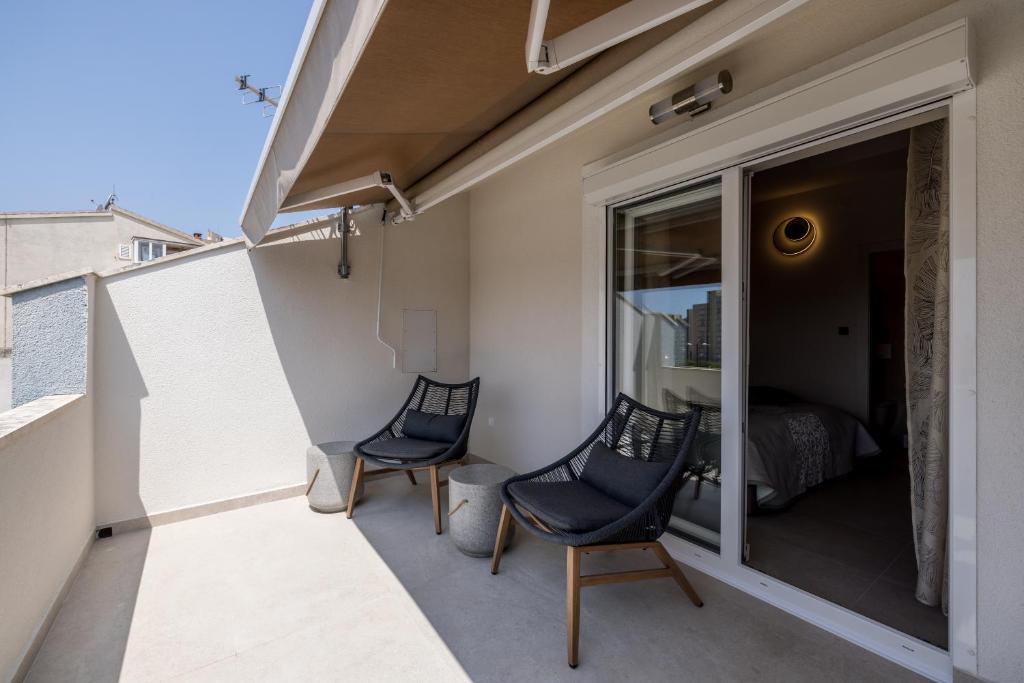 a balcony with two chairs and a bedroom at Guesthouse Rooms Split in Split