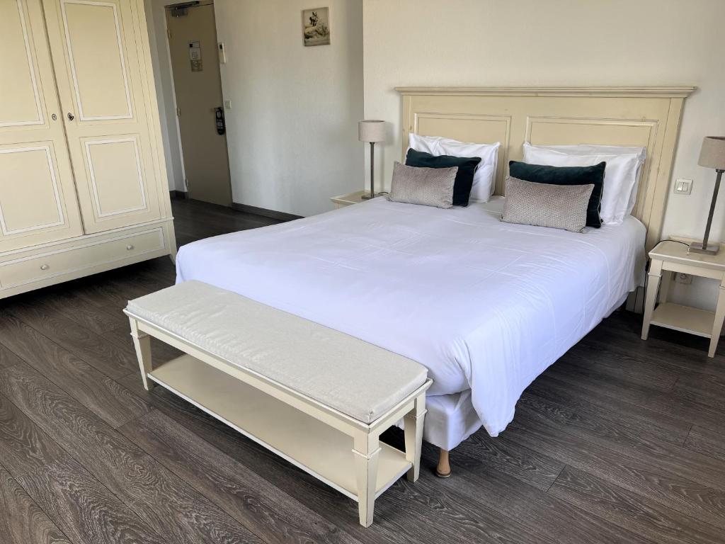 a bedroom with a large white bed with a bench at Hôtel Beau Site - Cap d'Antibes in Antibes