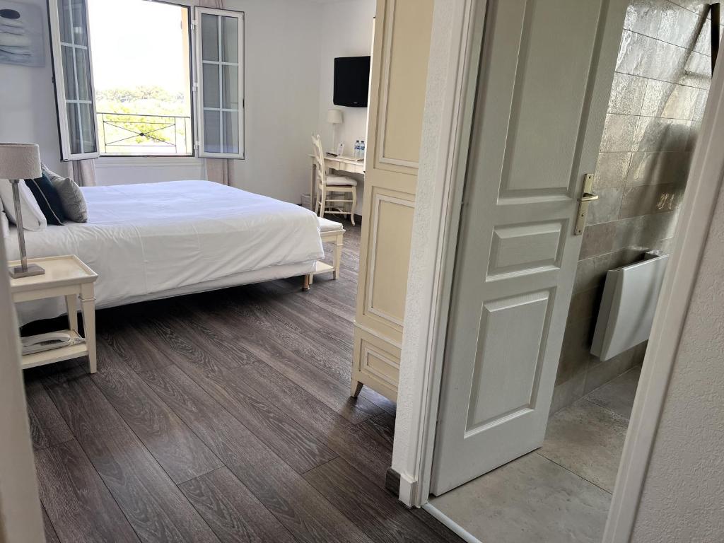 a bedroom with a bed and a desk and a window at Hôtel Beau Site - Cap d'Antibes in Antibes