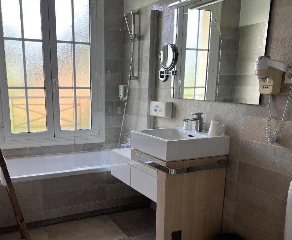a bathroom with a sink and a mirror and a tub at Hôtel Beau Site - Cap d'Antibes in Antibes