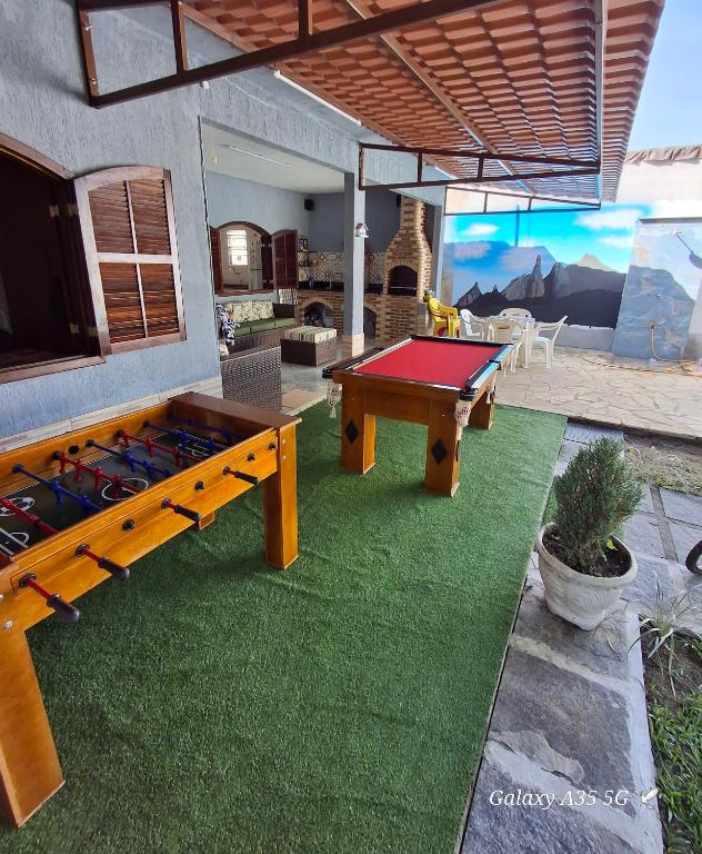 a patio with a ping pong table and a house at Casa no centro de Guapimirim, ar condicionado, piscina, churrasqueira, tranquilidade in Guapimirim