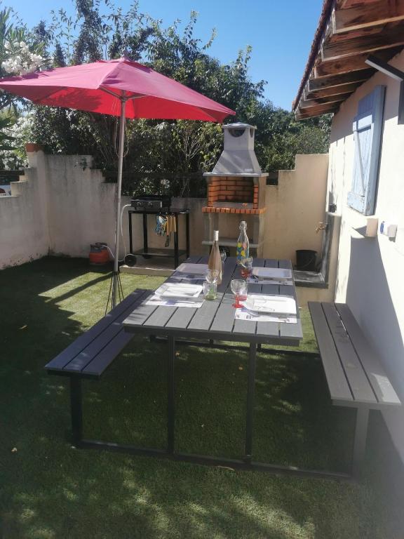 - une table de pique-nique avec un parasol rouge dans la cour dans l'établissement Au clos Huguette, à La Valette-du-Var