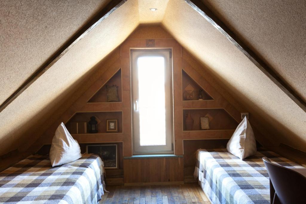 a attic room with two beds and a window at Mechtatel na Nekrasova in Saint Petersburg