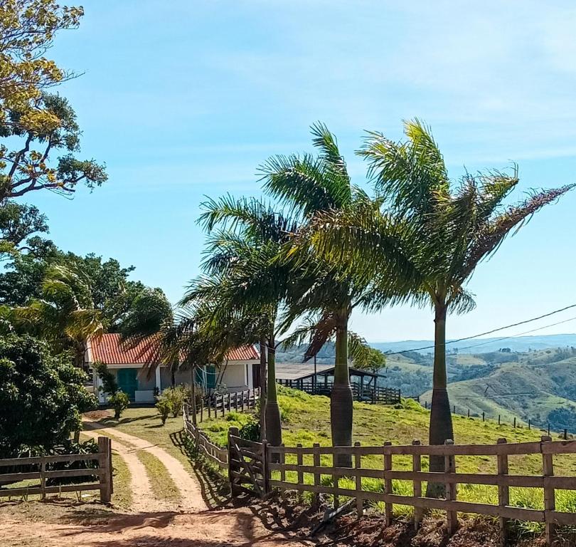 a dirt road with palm trees and a fence at Pousada das Colinas in Águas de Lindóia