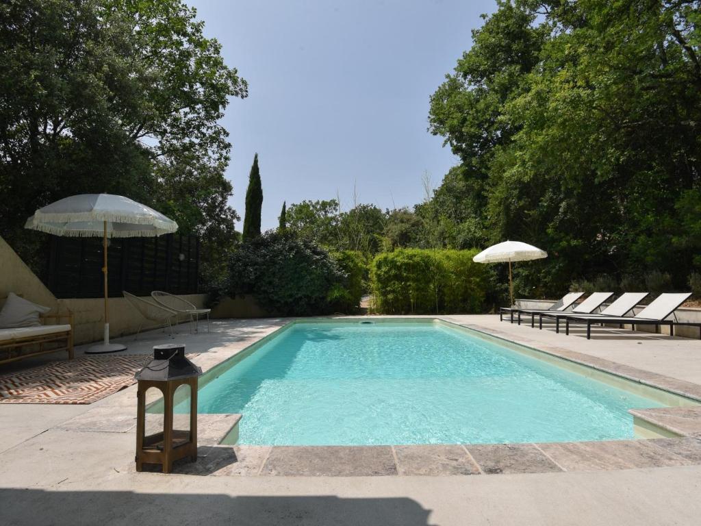 une piscine avec deux chaises et un parasol dans l'établissement Rosamania, au Thoronet