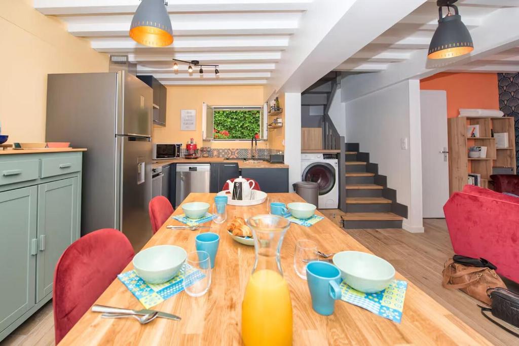 une cuisine et une salle à manger avec une table en bois et des chaises rouges dans l'établissement Chaleureuse Maison Familiale Etretat Plage, à Étretat